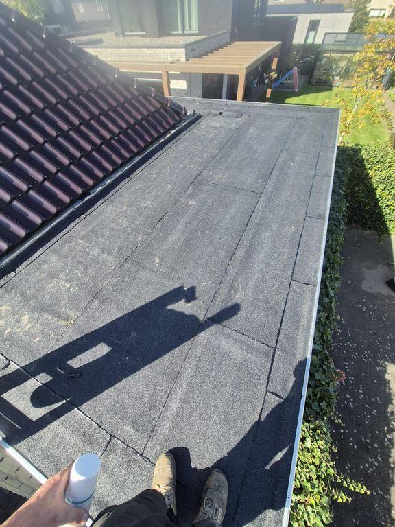 Plat dak met bitumen dakbedekking en dakrand, gefotografeerd tijdens inspectie of onderhoudswerkzaamheden.