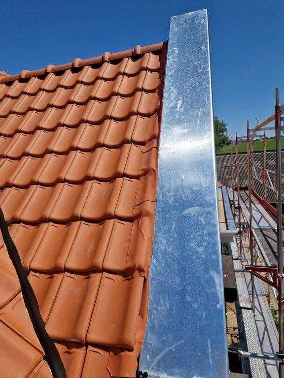Detail van nieuw geplaatst pannendak met zinken dakrandafwerking langs de gevel tijdens dakrenovatie.